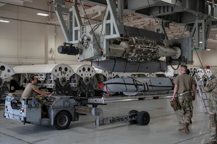 U.S. Airmen assigned to the 7th Munitions Squadron guide a Joint Air-to-Surface Standoff Missile into a Launcher Load Frame during a Multi-Role Pylon Load training event as part of the Death Strike: Trident Fury exercise at Dyess Air Force Base, Texas, June 22, 2026. The backshop training evaluated the crews' ability to rapidly configure and load heavy weapons directly onto launcher load frames within the facility. (U.S. Air Force photo by Airman 1st Class William Neal)