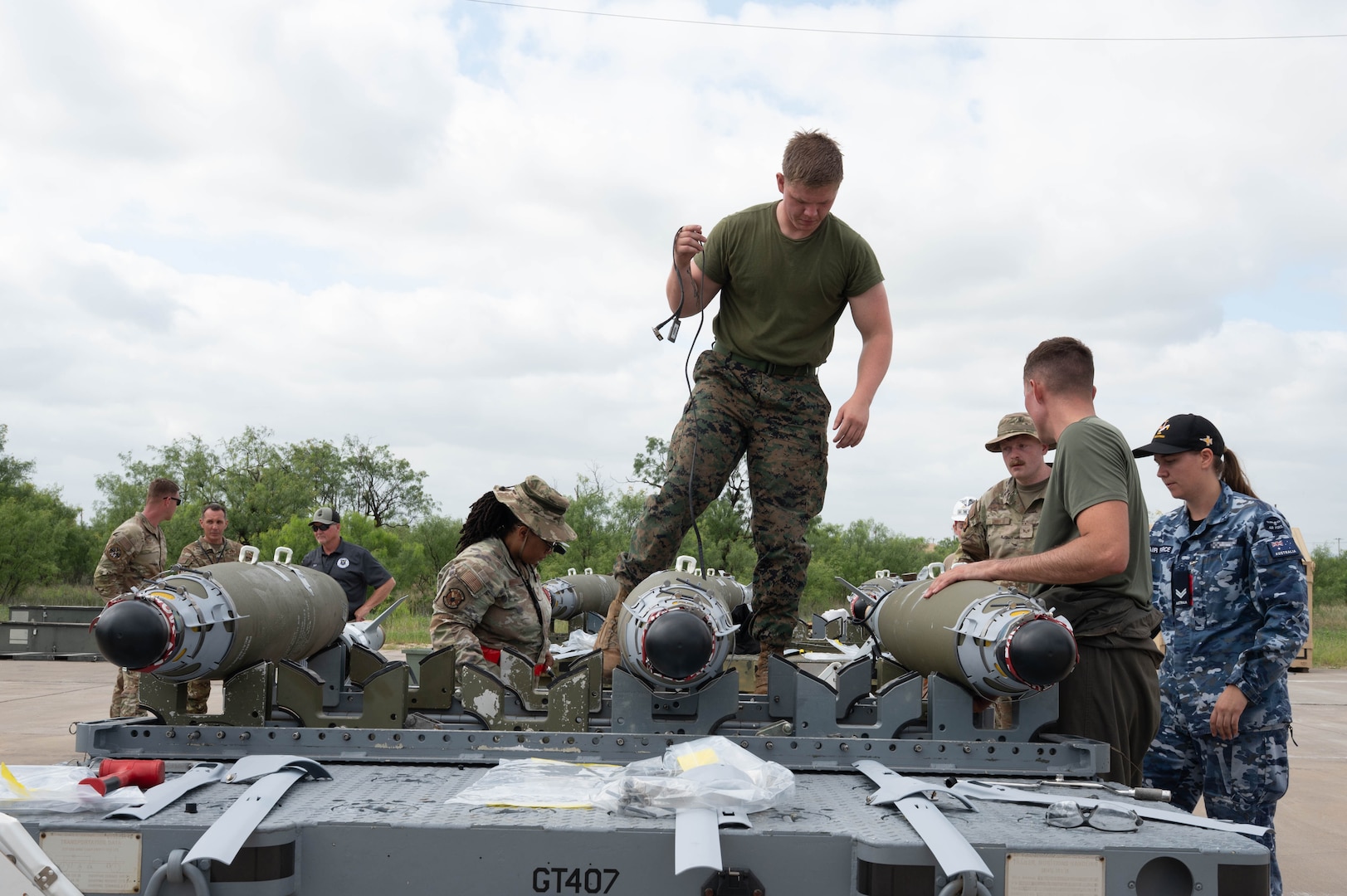 U.S. Air Force, U.S. Marine and Royal Australian Air Force service members work together to build conventional munitions during the Death Strike: Trident Fury exercise at Dyess Air Force Base, Texas, June 24, 2026. Death Strike: Trident Fury is a multi-day munitions production exercise focused on strengthening interoperability and proving the joint force's ability to rapidly scale operations in a simulated combat environment. (U.S. Air Force photo by Airman 1st Class William Neal) This photo was altered for security purposes by blurring out nametapes.