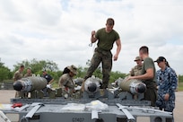 U.S. Air Force, U.S. Marine and Royal Australian Air Force service members work together to build conventional munitions during the Death Strike: Trident Fury exercise at Dyess Air Force Base, Texas, June 24, 2026. Death Strike: Trident Fury is a multi-day munitions production exercise focused on strengthening interoperability and proving the joint force's ability to rapidly scale operations in a simulated combat environment. (U.S. Air Force photo by Airman 1st Class William Neal) This photo was altered for security purposes by blurring out nametapes.