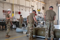 U.S. Airmen assigned to the 7th Munitions Squadron secure a hoist to a Joint Direct Attack Munition during the Death Strike: Trident Fury exercise at Dyess Air Force Base, Texas, June 22, 2026. The multi-day munitions production exercise focused on strengthening interoperability and proving the joint force's ability to rapidly scale operations in a simulated combat environment. (U.S. Air Force photo by Airman 1st Class William Neal)