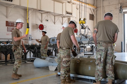U.S. Airmen assigned to the 7th Munitions Squadron secure a hoist to a Joint Direct Attack Munition during the Death Strike: Trident Fury exercise at Dyess Air Force Base, Texas, June 22, 2026. The multi-day munitions production exercise focused on strengthening interoperability and proving the joint force's ability to rapidly scale operations in a simulated combat environment. (U.S. Air Force photo by Airman 1st Class William Neal)