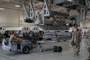 U.S. Airmen assigned to the 7th Munitions Squadron guide a Joint Air-to-Surface Standoff Missile into a Launcher Load Frame during a Multi-Role Pylon Load training event as part of the Death Strike: Trident Fury exercise at Dyess Air Force Base, Texas, June 22, 2026. The backshop training evaluated the crews' ability to rapidly configure and load heavy weapons directly onto launcher load frames within the facility. (U.S. Air Force photo by Airman 1st Class William Neal)
