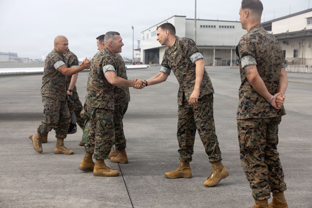 U.S. Marine Corps Lt. Col. Christopher Merrick, center right, commanding officer of Headquarters and Headquarters Squadron (H&HS), Marine Corps Air Station Iwakuni, and a native of Philadelphia, Pennsylvania, shakes hands with Brig. Gen Ralph Rizzo, center left, commanding general of Marine Corps Installations Pacific, and a native of Charlestown, Massachusetts, at MCAS Iwakuni, Japan, July 7, 2026. MCIPAC leadership visited MCAS Iwakuni to tour the air station, to speak with Marines, Sailors, and leaders about unit capabilities, and strengthen command relationships. (U.S. Marine Corps photos by Cpl. Brian Long)
