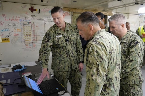 U.S. Navy Lt. Stephen Bishop (left), laboratory officer with Expeditionary Medical Facility (EMF) Bethesda, briefs Rear Adm. David M. Buzzetti (center), vice chief, U.S. Navy Bureau of Medicine and Surgery, and Master Chief Hospital Corpsman Jeffrey Tabor (right), senior enlisted advisor of Navy Reserve Medicine for the U.S. Navy Reserve, on blood product inventory tracking protocols within an Expeditionary Medical Facility (EMF). Maintaining a real-time, accurate log of critical medical logistics like blood products is a foundational element of medical command and control, ensuring the facility can sustain life-saving surgical capabilities during an operational surge. (U.S. Navy photo by Petty Officer 1st Class Jessica Seagraves)