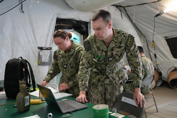 Lt. Matthew Boccuzzi (right), health care administrator, assigned to Expeditionary Medical Facility (EMF) Bethesda, tracks simulated casualties in patient administration during an EMF training evolution at Naval Expeditionary Medicine Warfighter Development Center (NEMWDC), Camp Pendleton, California, May 18, 2026. Patient administration personnel maintain accountability and movement of patients throughout the EMF, supporting the EMF’s ability to deliver organized medical care in an expeditionary environment. (U.S. Navy photo by Petty Officer 2nd Class Leandra Mojica)