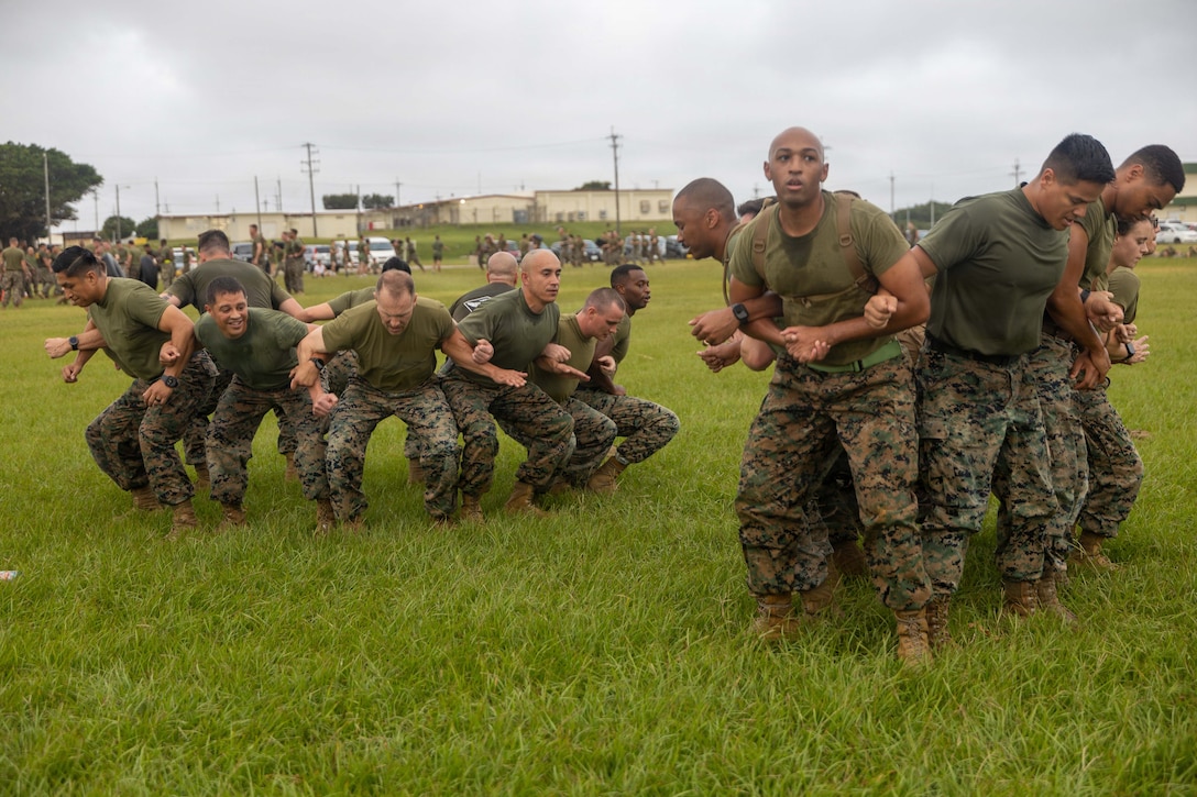 Two small groups of Marines link arms in a circle with their backs facing the middle of the circle.