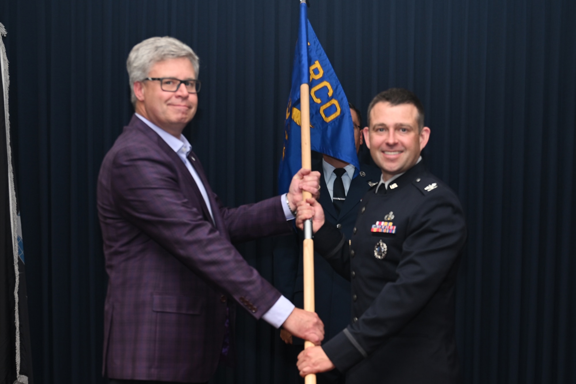 U.S. Space Force Col. Paul A. LaTour, incoming Space Rapid Capabilities Office’s Advanced Capabilities Acquisition Delta systems program director, right, receives the guidon from Dr. Natahan Dalrymple, SpRCO acting and technical director, left, at Kirtland Air Force Base.