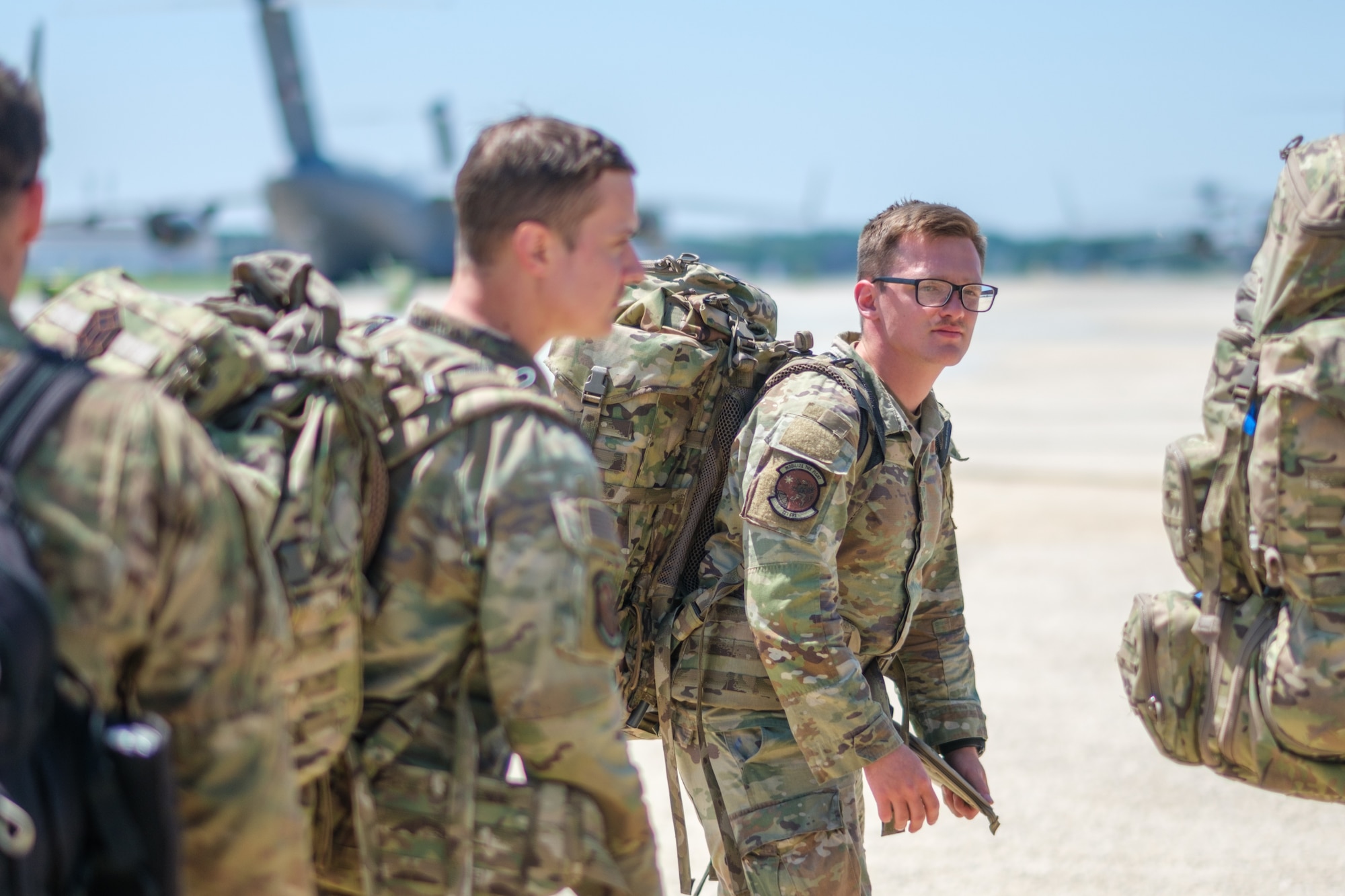 Airmen in uniform stand in a line in front of a cargo plane