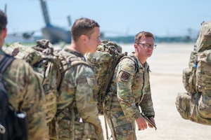 Airmen in uniform stand in a line in front of a cargo plane