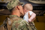 Uniformed service member kisses baby
