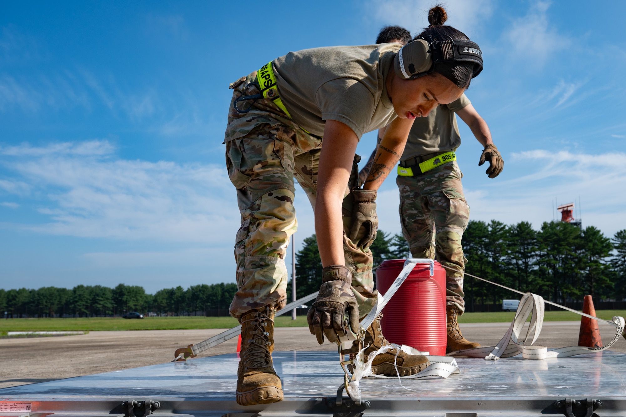 U.S. Air Force Airman 1st Class Lorena Gouveia, 305th Aerial Port Squadron cargo specialist, tightens a ratchet strap during a Port Dawg Rodeo at Joint Base McGuire-Dix-Lakehurst, N.J., July 10, 2026. Gouveia and her teammates worked together to complete the 10k standard forklift obstacle course portion of the rodeo. (U.S. Air Force photo by Airman 1st Class Haeleigh Bayle)