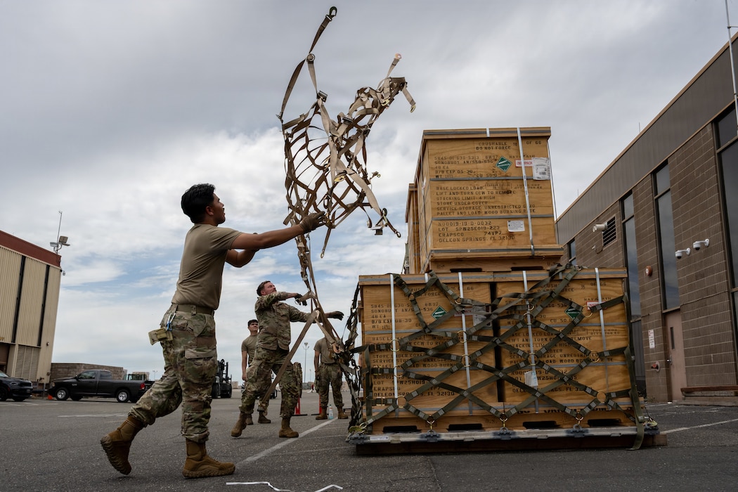 Airmen throw cargo straps over cargo.