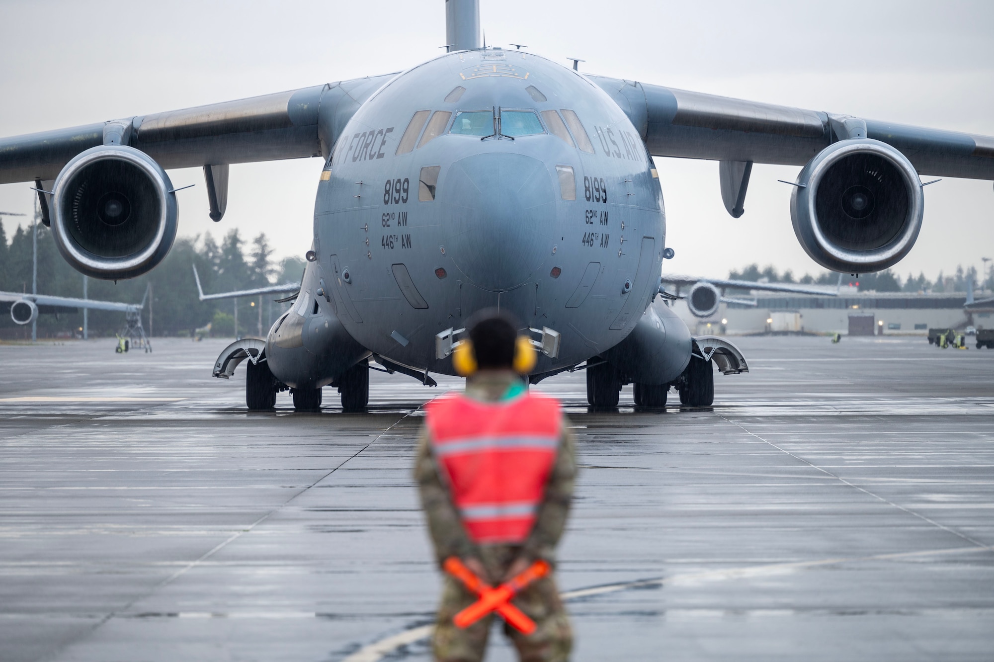 a symmetrical image with a military plane in the background and a blurry marshaling official in the forground