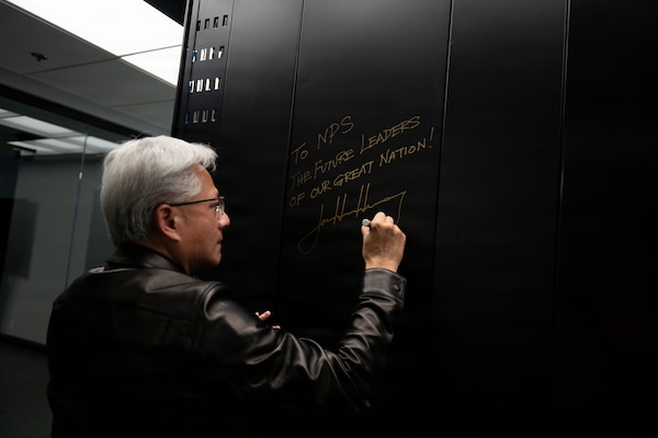 Jensen Huang, founder and CEO of NVIDIA, signs the exterior panel of the NVIDIA DGX GB300 AI supercomputer at the Naval Postgraduate School (NPS) in Monterey, California, July 22, 2026. The system supports NPS and approved research partners conducting defense-focused research in artificial intelligence, cyber, autonomy, modeling and operational analysis. (U.S. Navy photo by Mass Communication Specialist 2nd Class Abreen Padeken)