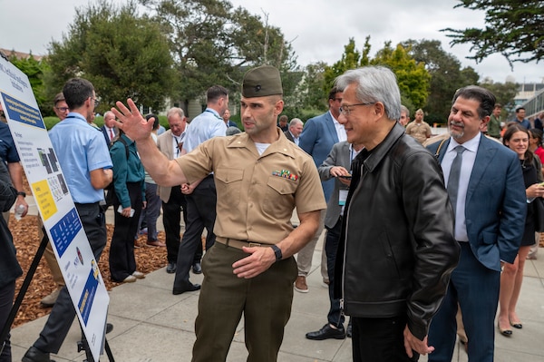 U.S. Marine Corps Maj. Robert Fusco, a Naval Postgraduate School (NPS) student, briefs Jensen Huang, founder and CEO of NVIDIA, during a research poster session at NPS in Monterey, California, July 22, 2026. NPS provides defense-focused graduate education and applied research to support the operational effectiveness and technological leadership of the naval service. (U.S. Navy photo by Mass Communication Specialist 2nd Class Janiel Adames)