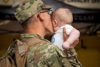 Uniformed service member kisses baby