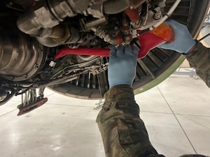 A thermoplastic polyurethane (TPU) fuel funnel is used to service an engine starter at McConnell Air Force Base, Kansas, 17 July, 2026. The 3-D printed TPU funnel was created by McConnell's Innovation Lab to increase servicing efficiency while doing maintenance on engine starters by maintenance professionals. (Courtesy Photo)