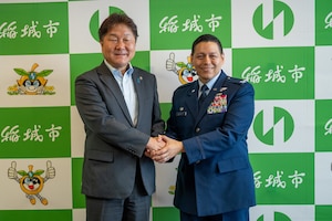 An Airman poses for a photo holding hands with a Japanese mayor.