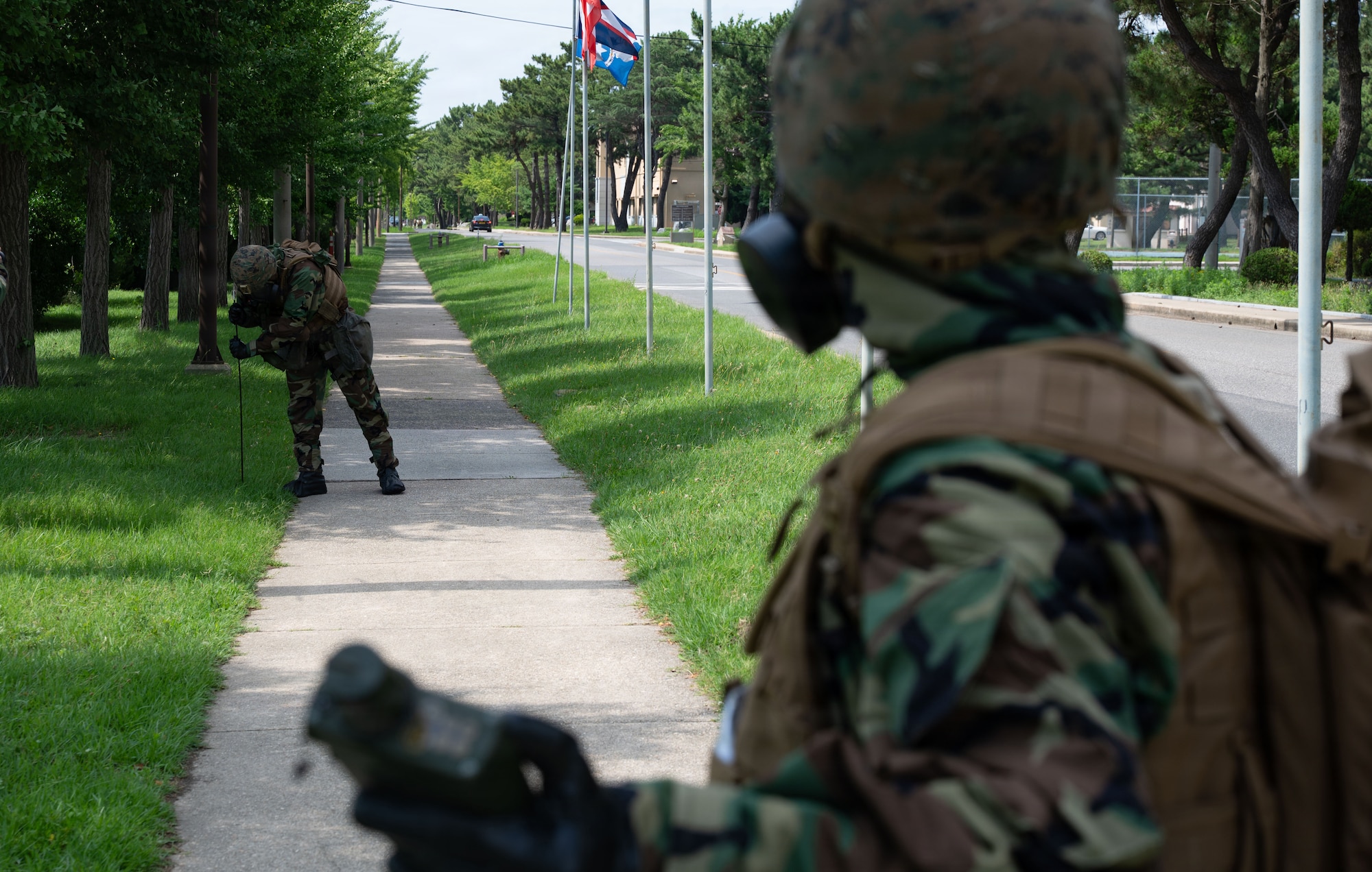 U.S. Marine Lance Cpl. Garrett Bruening, left, and Everett Bonilla, right, Chemical, Biological, Radiological and Nuclear responders assigned to Marine Wing Support Squadron 171, Marine Air Station, Iwakuni, Japan, plant cordon markers around a simulated CBRN contaminated area during exercise Beverly Sentinel 26-4 at Kunsan Air Base, Republic of Korea, July 22, 2026. Throughout the exercise, a joint team of Airmen and Marines demonstrated their ability to execute core mission tasks in unison, from defending the base to projecting power, showcasing the strategic advantage of U.S. joint warfighters.