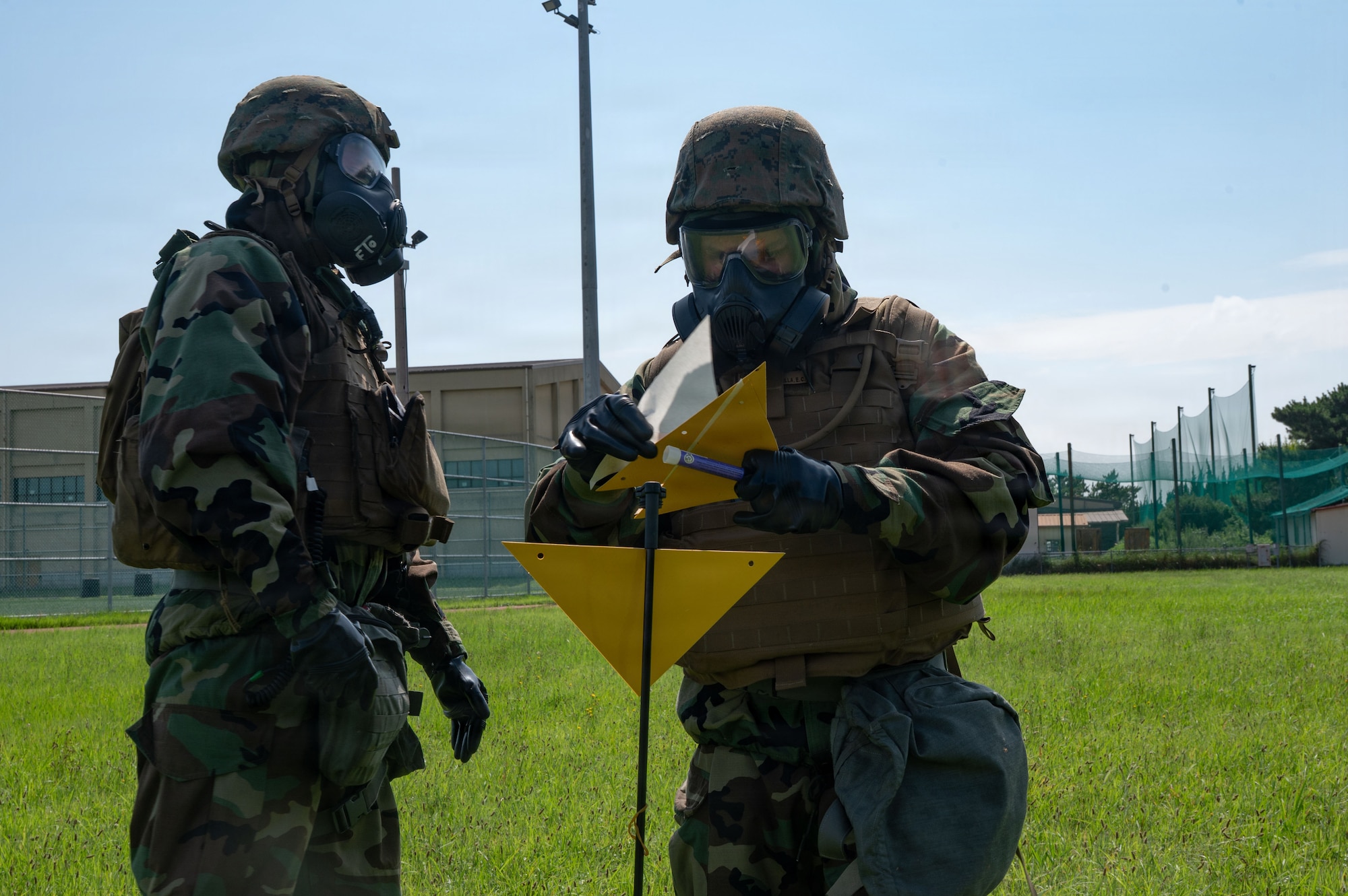 U.S. Marine Lance Cpl. Garrett Bruening, center, and Everett Bonilla, left, Chemical, Biological, Radiological and Nuclear responders assigned to Marine Wing Support Squadron 171, Marine Air Station, Iwakuni, Japan, mark flags around a simulated CBRN contaminated area during exercise Beverly Sentinel 26-4 at Kunsan Air Base, Republic of Korea, July 22, 2026. Throughout the exercise, a joint team Airmen and Marines demonstrated their ability to execute core mission tasks in unison, from defending the base to projecting power, showcasing the strategic advantage of U.S. joint warfighters.