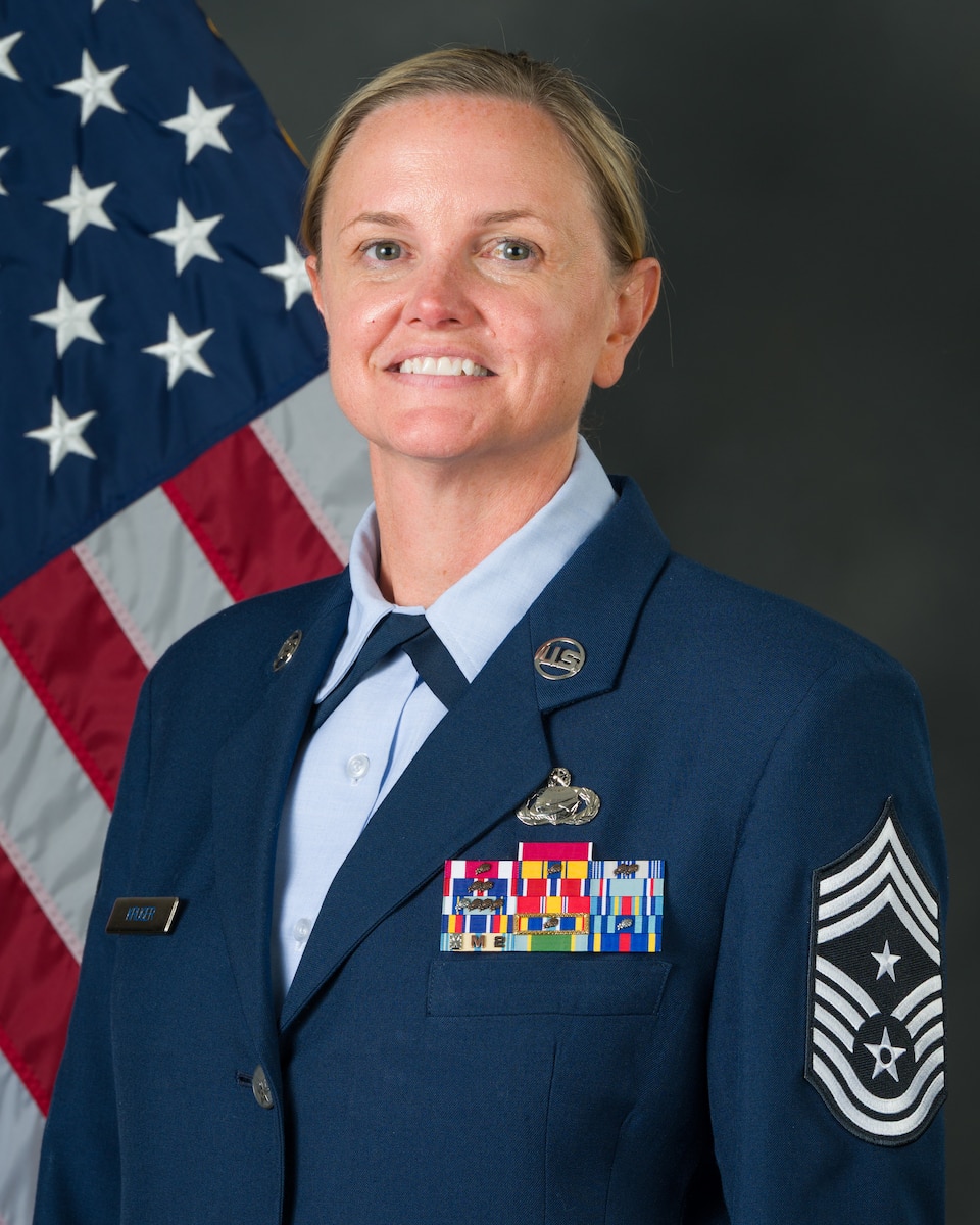 Female service member poses for a photo in front of a flag