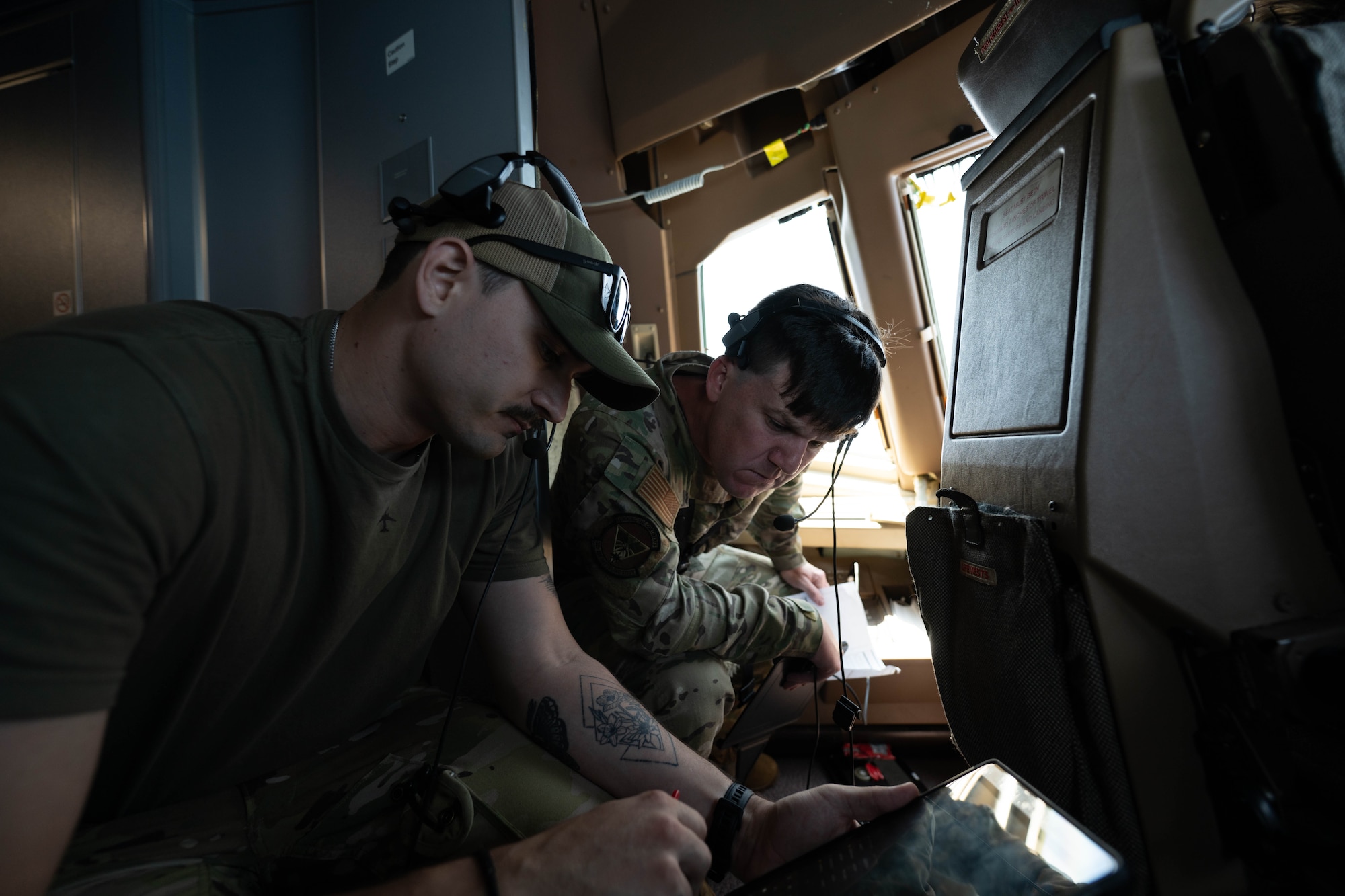 U.S. Air Force Senior Airman Brandon Rivas, 32nd Air Refueling Squadron instructor boom operator, goes over standard operating procedures with Tech. Sgt. Jonathan Friesz, 32nd ARS boom operator, during a flight over the Atlantic Ocean, June 29, 2026.