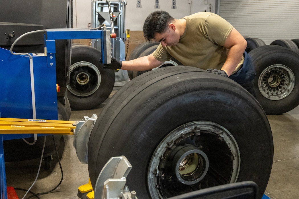 Airman loads a tire onto a machine