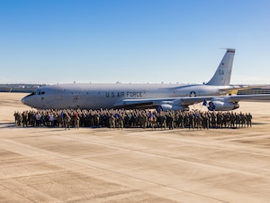 A group photo with an airplane in the background