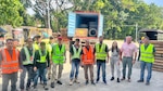 People in safety gear pose at an outdoor work site.