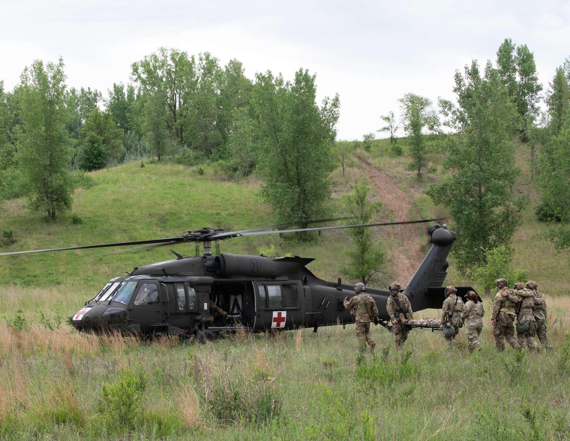 U.S. Air Force Airmen from the 133rd Security Forces Squadron load simulated patients onto a UH-60 Black Hawk helicopter from Charlie Company, 2nd Battalion, 211th Aviation Regiment, 34th Combat Aviation Brigade, Minnesota National Guard, in Arden Hills, Minn., June 11, 2026.