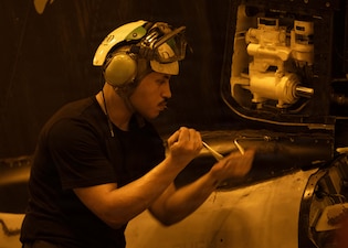A U.S. Sailor, assigned to Strike Fighter Squadron (VFA) 103, maintains an F/A-18E Super Hornet in the hangar bay of Nimitz-class aircraft carrier USS George H.W. Bush (CVN 77), July 13, 2026. George H.W. Bush is deployed to the U.S. 5th Fleet area of operations to support maritime security and stability in the Middle East. (U.S. Navy photo)