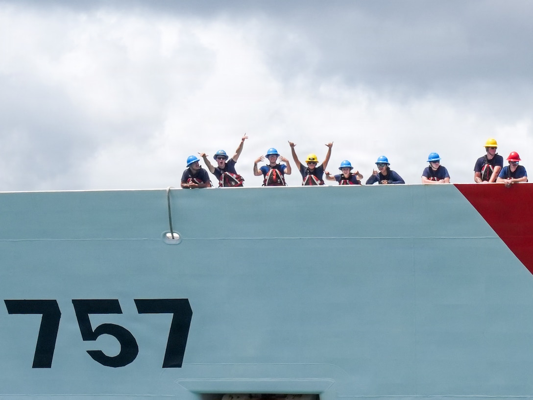 Members assigned to Coast Guard Cutter Midgett (WMSL 757) wave to families on the pier before mooring at Coast Guard Base Honolulu July 20, 2026. Throughout the deployment, Midgett operated under the tactical control of U.S. Navy 7th Fleet, supporting efforts to promote a free and open Indo-Pacific. (U.S. Coast Guard photo by Petty Officer 3rd Class Jennifer Nilson)