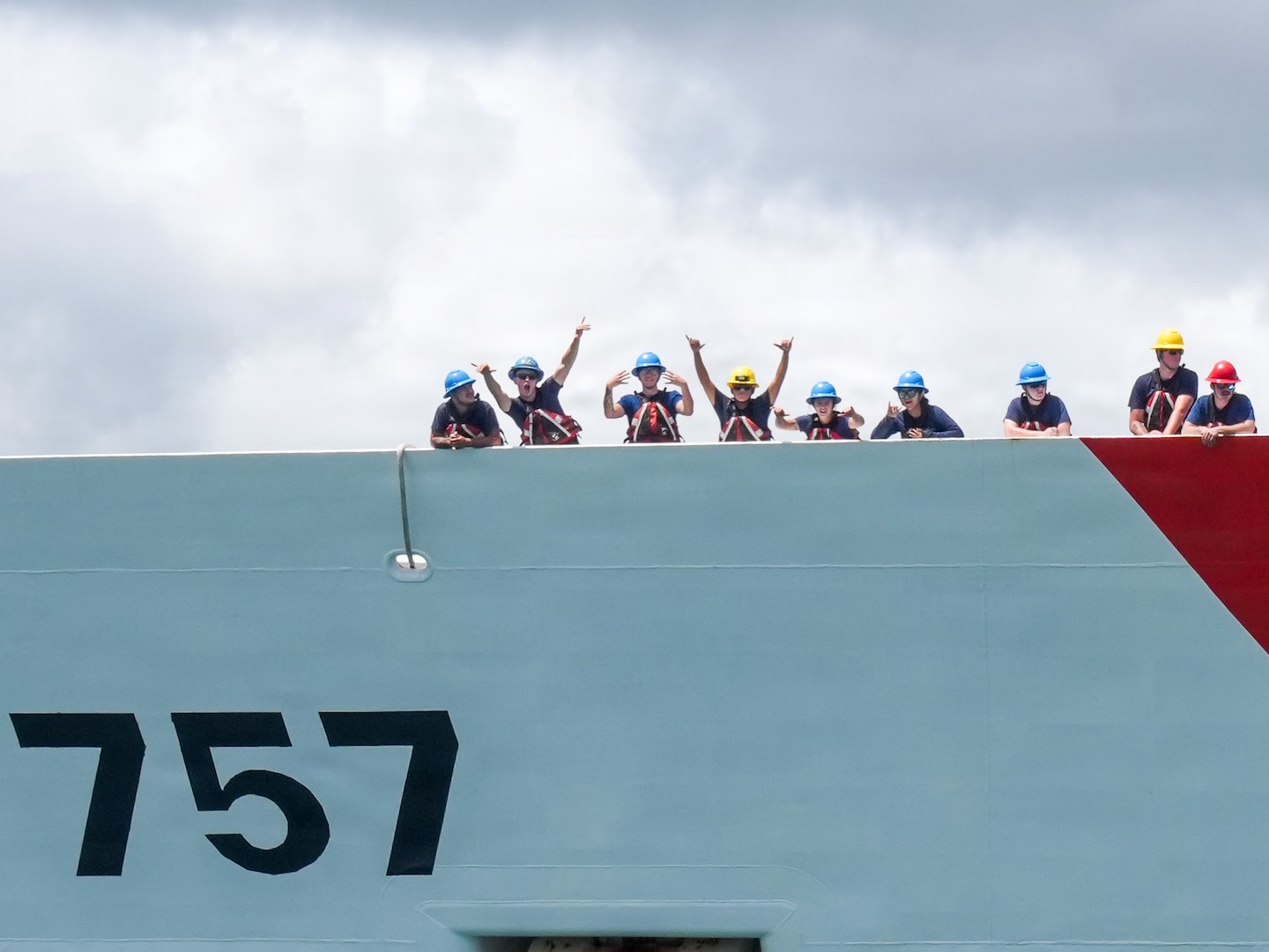 Members assigned to Coast Guard Cutter Midgett (WMSL 757) wave to families on the pier before mooring at Coast Guard Base Honolulu July 20, 2026. Throughout the deployment, Midgett operated under the tactical control of U.S. Navy 7th Fleet, supporting efforts to promote a free and open Indo-Pacific. (U.S. Coast Guard photo by Petty Officer 3rd Class Jennifer Nilson)