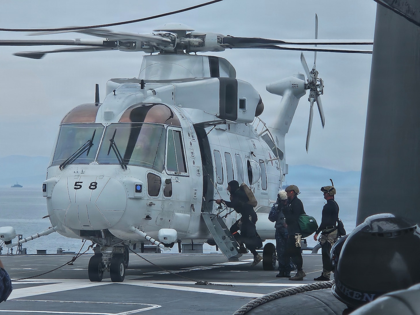 U.S. Navy Explosive Ordnance Disposal Mobile Unit 5 and Japan Maritime Self-Defense Force explosive ordnance disposal sailors board a JMSDF MCH-101 helicopter during mine countermeasure diving operations as part of Mine Warfare Exercise (MINEX) 2JA, July 14, 2026. 2JA is part of a year-long series of bilateral exercises between the U.S. Navy and Japan Maritime Self-Defense Force MSDF to strengthen interoperability and increase proficiency in mine countermeasure operations. (U.S. Navy photo by Lt. Jacob Kinnear)
