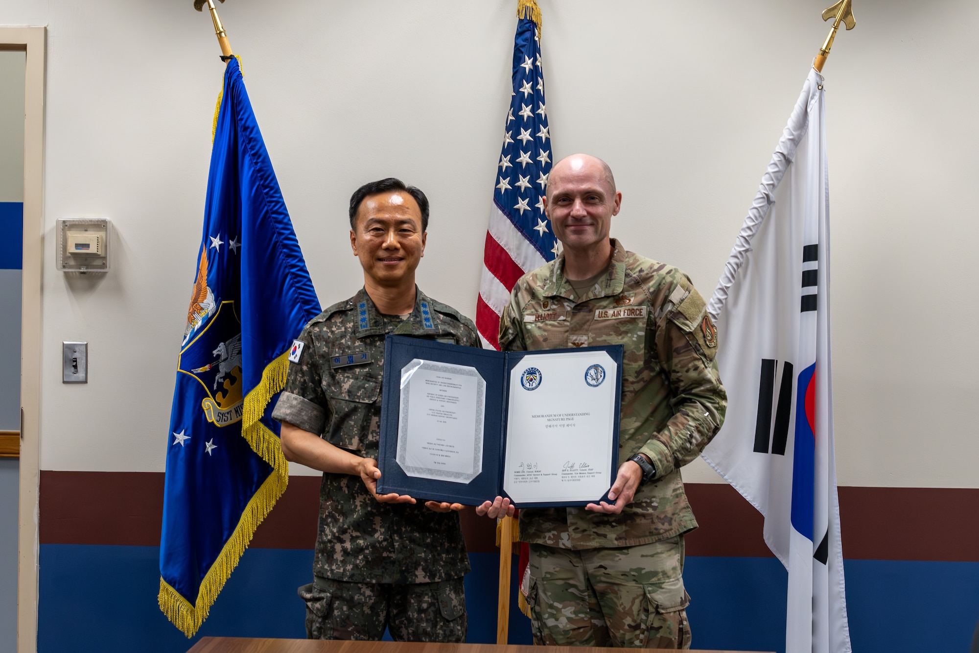 A USAF and ROKAF commander pose for a photo holding a signed memorandum.