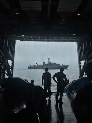 U.S. Navy Explosive Ordnance Disposal Mobile Unit 5 and Japan Maritime Self-Defense Force sailors watch from the rear hatch of JMSDF mine sweeper tender JS Bungo (MST-464) as ocean mine sweeper JS Awaji (MSO-304) passes during Mine Warfare Exercise 2JA, July 14, 2026. 2JA is part of a year-long series of bilateral exercises between the U.S. Navy and JMSDF to strengthen interoperability and increase proficiency in mine countermeasure operations. (U.S. Navy photo by Lt. Jacob Kinnear)