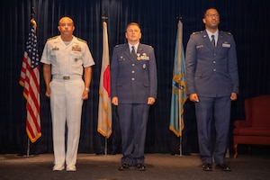 Three men stand at attention.