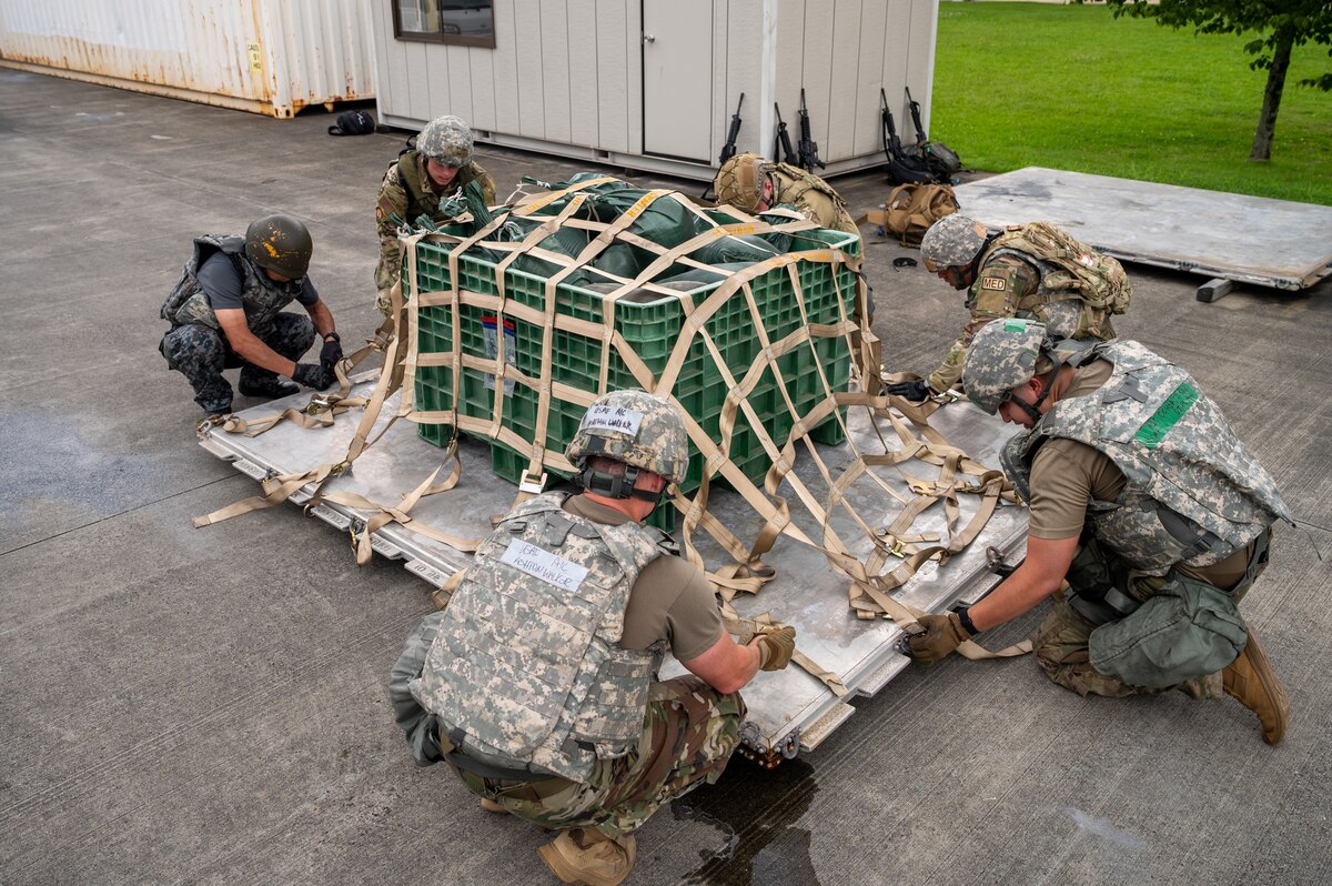 Airmen secure straps on a pallet.