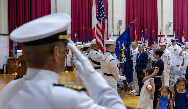 YOKOSUKA, Japan (July 23, 2026) — Service members and guests stand for the presentation of colors and the playing of the national anthem during U.S. Navy Medicine Readiness and Training Command Yokosuka’s change of command ceremony at Commander, Fleet Activities Yokosuka's C2 Auditorium. The ceremony marked the transfer of command from Capt. Torrin W. Velazquez to Capt. Joshua A. Miller. USNMRTC Yokosuka delivers patient- and family-centered healthcare while developing and delivering trained, ready medical forces in support of U.S. Indo-Pacific Command. (U.S. Navy photo by Daniel Taylor/USNH Yokosuka Public Affairs)