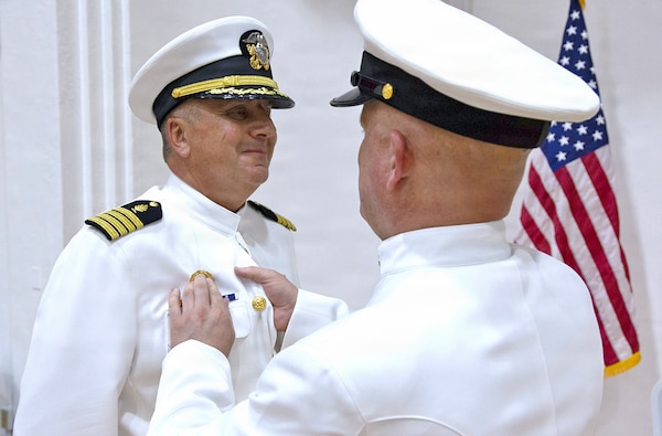 YOKOSUKA, Japan (July 23, 2026) — Capt. Joshua A. Miller receives his command pin from U.S. Navy Medicine Readiness and Training Command (USNMRTC) Yokosuka’s Command Master Chief Matt Haylow during a change of command ceremony at Commander, Fleet Activities Yokosuka's C2 Auditorium. During the ceremony, Miller relieved Capt. Torrin Velazquez as commanding officer of USNMRTC Yokosuka and director of U.S. Naval Hospital (USNH) Yokosuka. USNH Yokosuka delivers patient- and family-centered healthcare while developing and delivering trained, ready medical forces in support of U.S. Indo-Pacific Command. (U.S. Navy photo by Daniel Taylor/USNH Yokosuka Public Affairs)