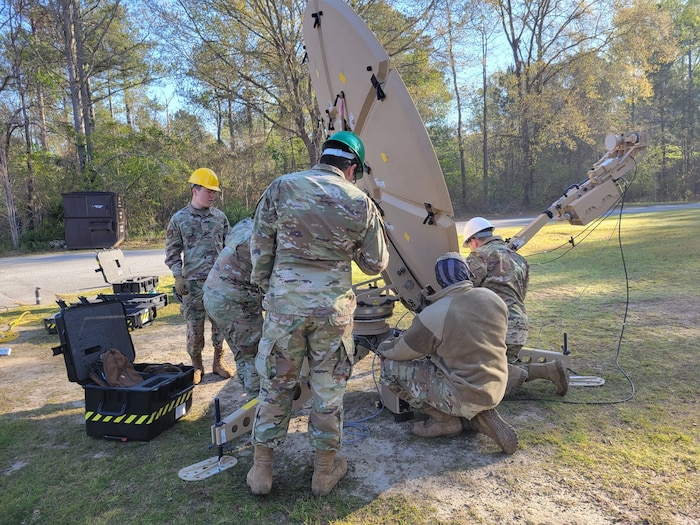Military personnel work on an antenna
