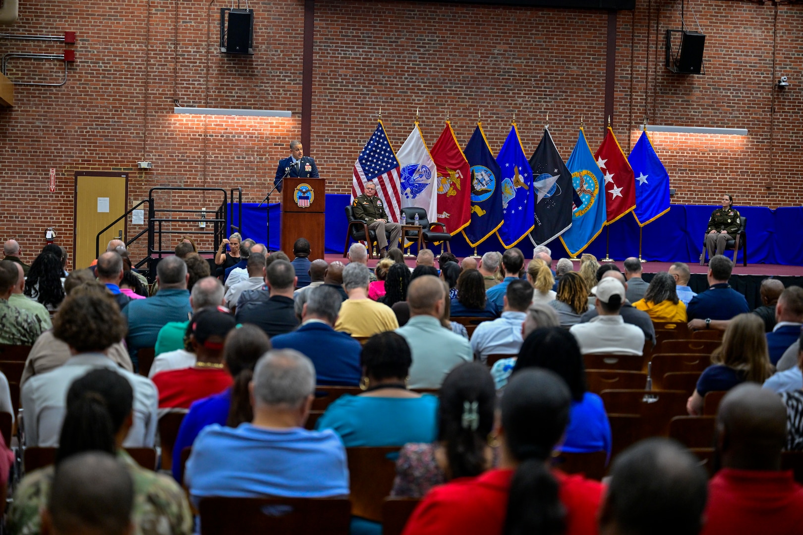 A one-star Air Force General standing on stage delivering remarks during a ceremony