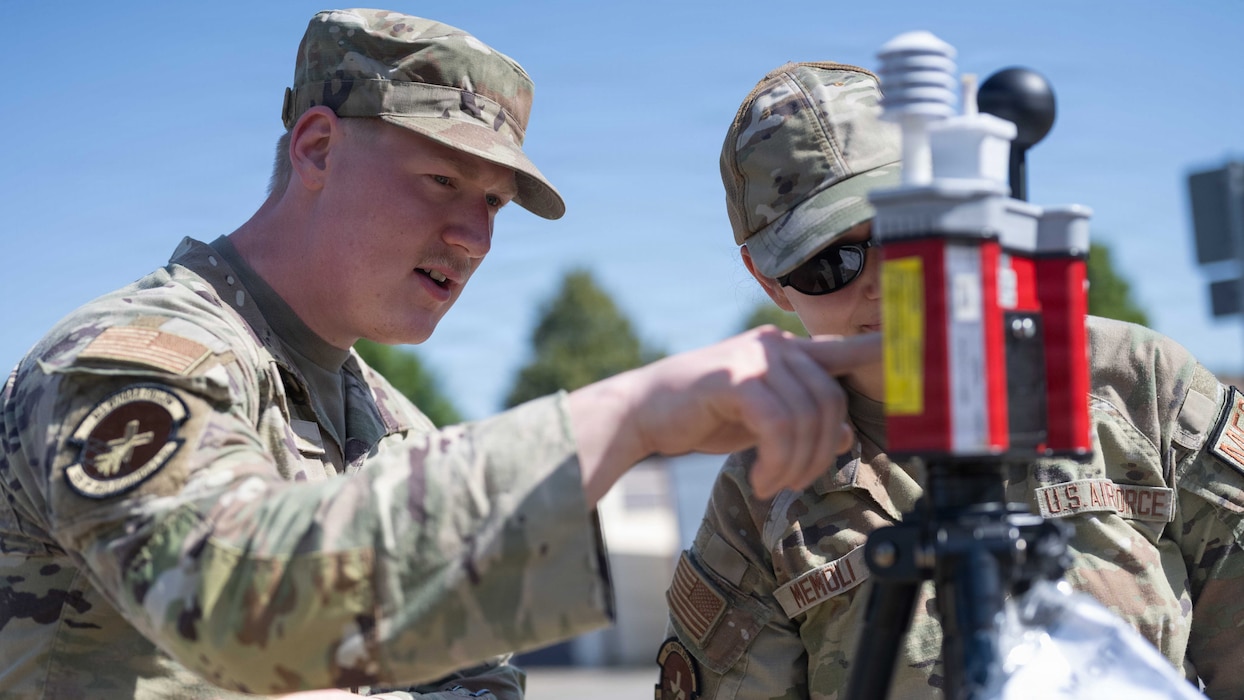 U.S. Air Force Senior Airman John Cates, 52nd Operational Medical Readiness Squadron bioenvironmental engineering technician, left, and Senior Airman Kellie Memoli, 52nd OMRS bioenvironmental engineering technician, record a wet bulb globe temperature reading at Spangdahlem Air Base, Germany, June 25, 2026. Bioenvironmental engineers use the wet bulb globe temperature monitor to assess environmental heat stress by measuring air temperature, humidity, radiant heat and wind conditions. (U.S. Air Force photo by Staff Sgt. Darius Frazier)