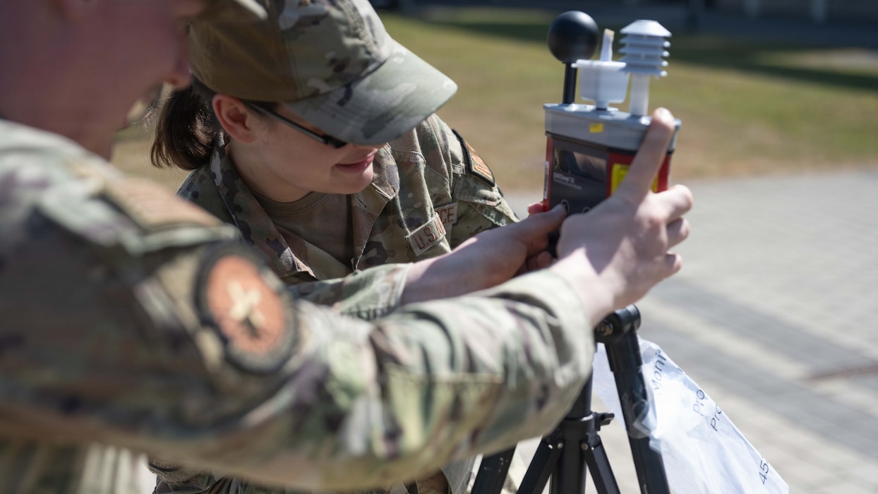 U.S. Air Force Senior Airman John Cates, 52nd Operational Medical Readiness Squadron bioenvironmental engineering technician, left, and Senior Airman Kellie Memoli, 52nd OMRS bioenvironmental engineering technician, record a wet bulb globe temperature reading at Spangdahlem Air Base, Germany, June 25, 2026. During a record high heatwave, the bioenvironmental engineering team is tasked with ensuring the base stays current on active heat advisories. (U.S. Air Force photo by Staff Sgt. Darius Frazier)