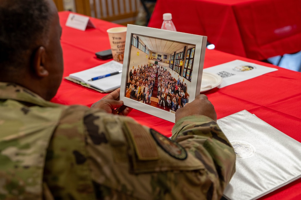 U.S. Air Force Col. Ralph Elliott, Europe-Air Forces Africa command chaplain, holds a framed photo of a local congregation during a visit to Spangdahlem Air Base, Germany, June 24, 2026. Elliott previously served at Spangdahlem AB five years ago, making the visit an opportunity to reconnect with the chapel community and reflect on its continued impact across the installation. (U.S. Air Force photo by Airman 1st Class Kacie Ramos)