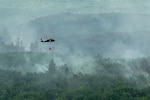 A U.S. Army National Guard UH-60 Black Hawk helicopter assigned to the 34th Combat Aviation Brigade transports water in a water bucket over wildfires in Northern Minnesota, July 15, 2026. Minnesota Gov. Tim Walz declared a peacetime emergency on July 12, activating the Minnesota National Guard to support civil authorities with aerial wildfire suppression operations. This joint Army and Air National Guard response showcases the state's readiness to protect life, preserve property and support Minnesota communities. Photo by Staff Sgt. Tylin Rust.