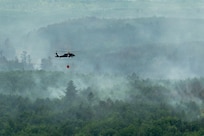 A U.S. Army National Guard UH-60 Black Hawk helicopter assigned to the 34th Combat Aviation Brigade transports water in a water bucket over wildfires in Northern Minnesota, July 15, 2026.