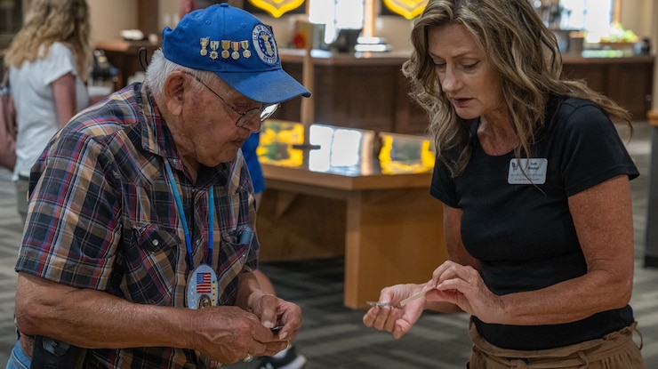 Kelly Weiand, North Dakota Military Outreach Program military outreach specialist (right), provides resources to Freddie Rios, a military retiree, during Retiree Appreciation Day at Minot Air Force Base, North Dakota, July 12, 2024. A number of agencies attended Retiree Appreciation Day to provide support to military retirees. (U.S. Air Force photo by Senior Airman Kyle Wilson)
