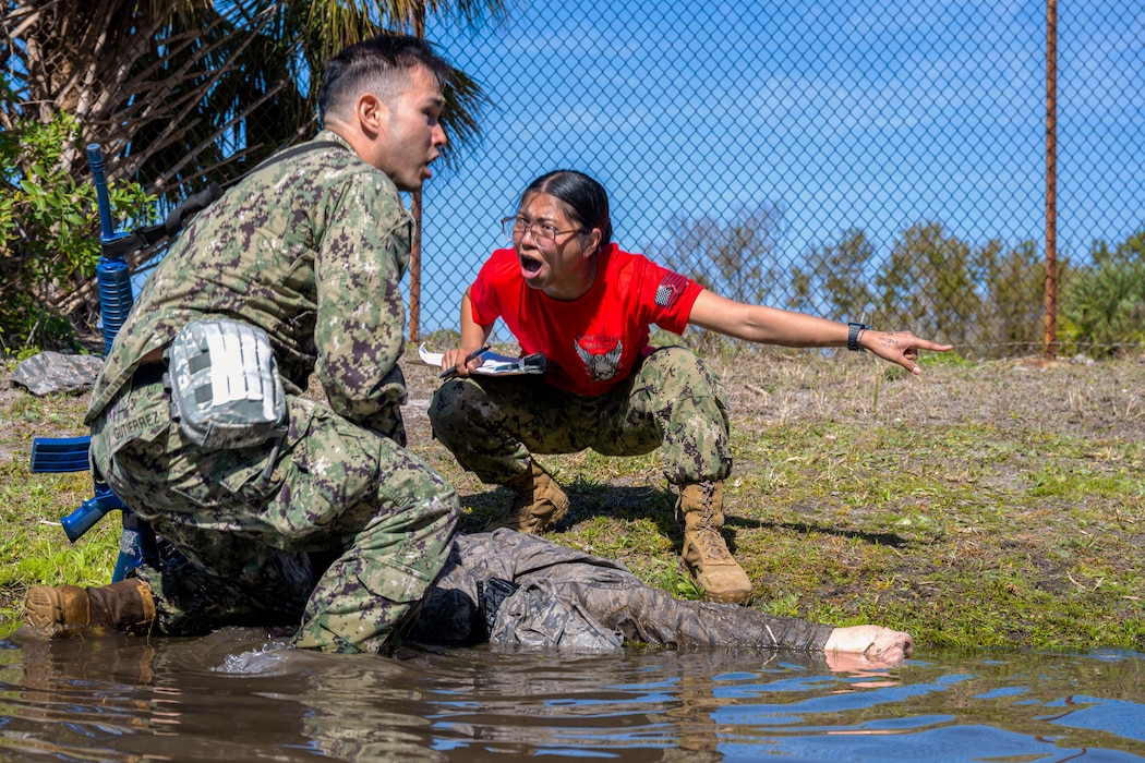 U.S. Navy Hospital Corpsman 3rd Class Ramon Gutierrez, Operation Blue Horizon trainee, left, is tested on Tactical Combat Casualty Care skills by Hospital Corpsman 2nd Class Jc Alvaran, OBH TCCC instructor, at MacDill Air Force Base, Florida, March 4, 2025. Trainees certifying in TCCC during OBH must drag simulated patients from an unsafe environment after an intense physical training portion before administering first response care. (U.S. Air Force photo by Senior Airman Derrick Bole)