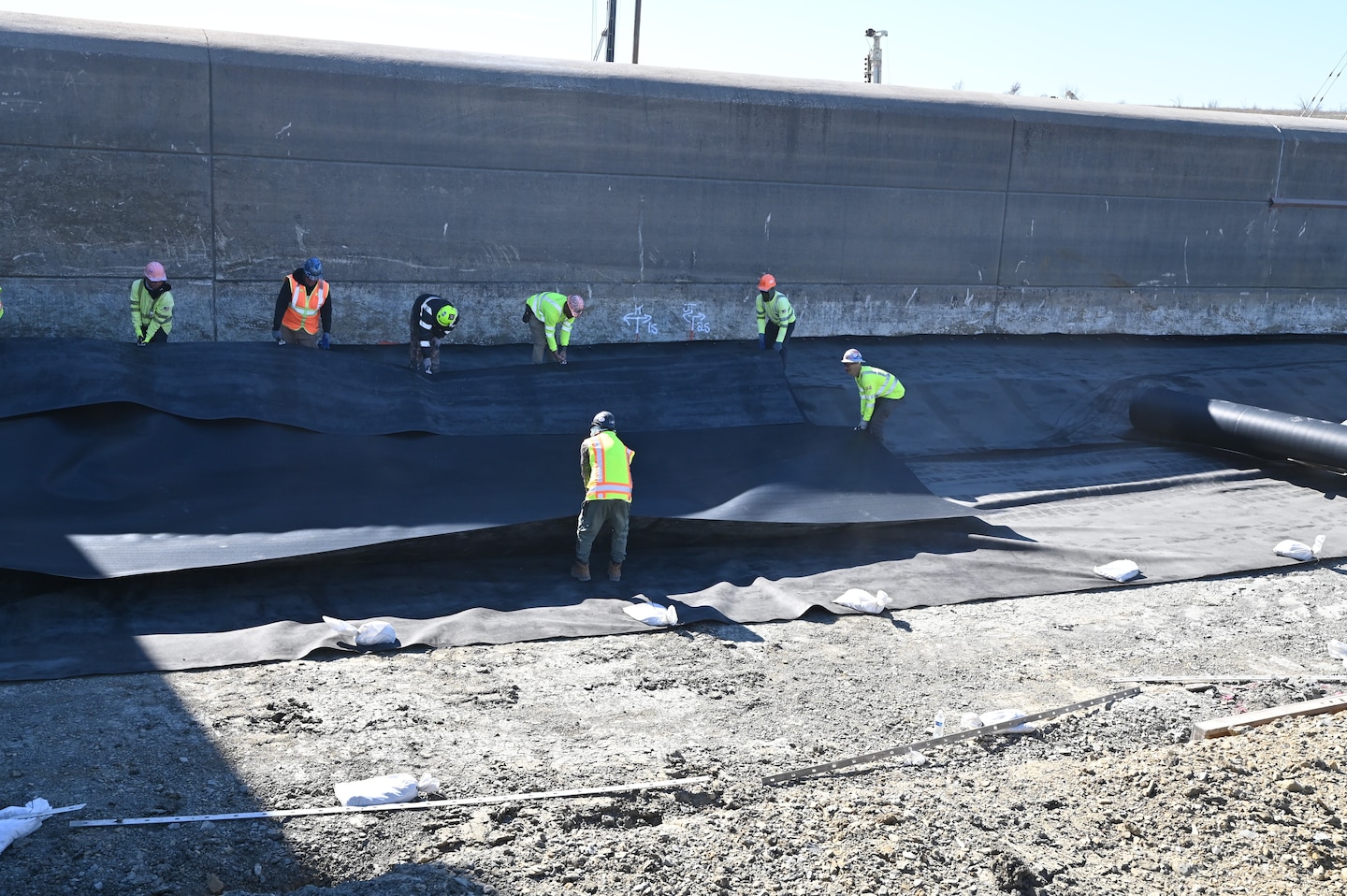 Construction crews installing an upstream geomembrane blanket designed to limit seepage beneath the spillway, reducing water pressures that can develop beneath the concrete during flood operations. This is one of many improvements being made as part of the Lewisville Spillway Modification Program. In addition, engineers installed more than 70 high-capacity post-tensioned anchors through the spillway weir and into the underlying bedrock. These anchors increase the spillway's resistance to uplift forces and improve overall structural stability. Additional improvements include reinforcing portions of the spillway apron with 936 rock dowels and restoring disturbed areas once construction is complete.